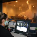 A woman wearing a mask sitting at a desk with a computer.