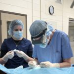 A man and woman in surgical masks working on something.