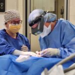 A surgeon and a nurse are working together.
